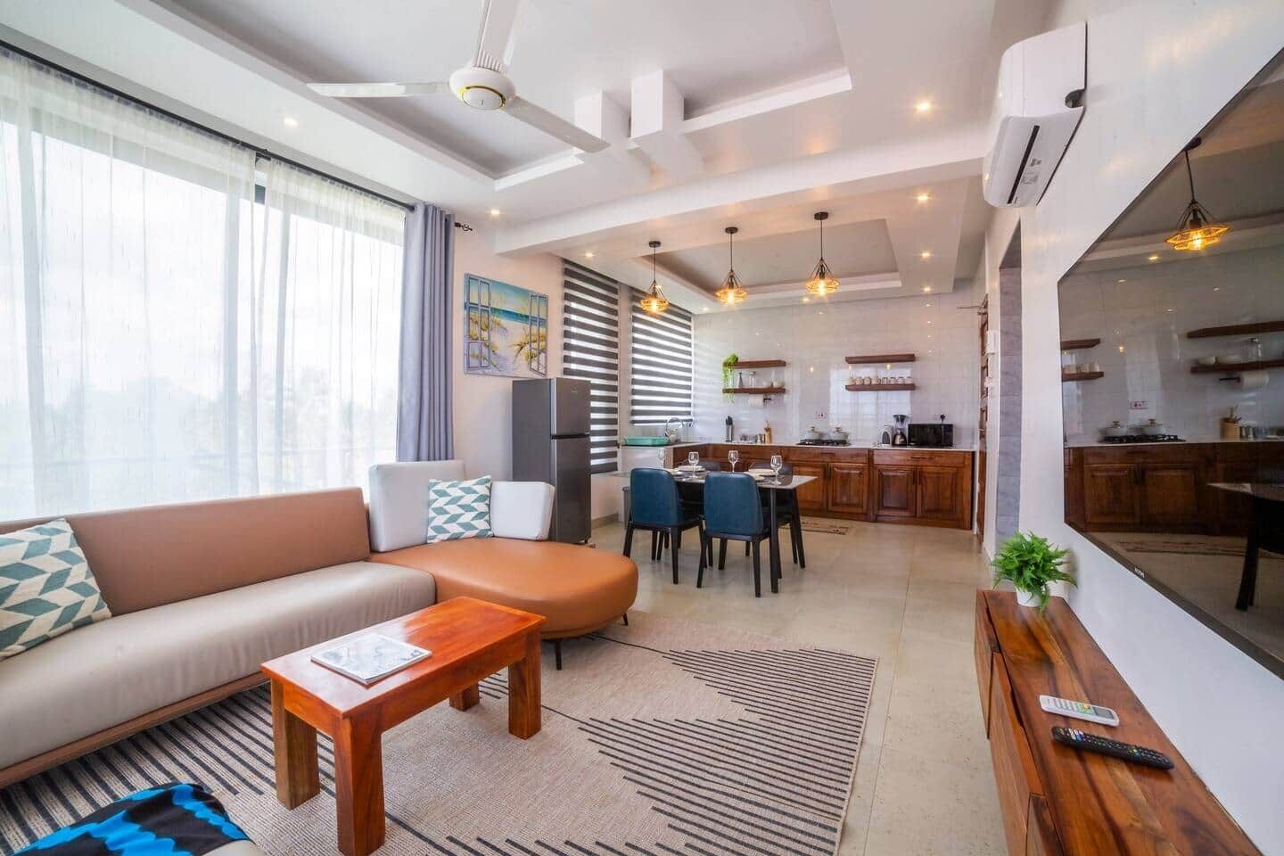 Una sala de estar moderna con sofá, mesa de comedor y zona de cocina.