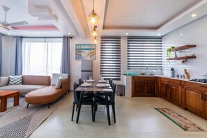 A modern living room with a sofa, dining table, and kitchen area. - Private 1 BDR Apt| w/Pool | Beachwalk - Generator (Jambiani)