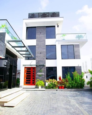 A modern hotel with a glass facade, a red door, and a balcony. - New Urban Oasis Apt w/Pool + Hot tub + Gym (Dar es Salaam)