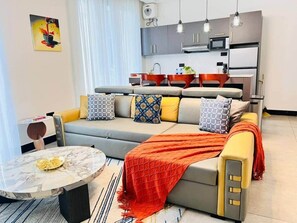 Una sala moderna con un sofá, una mesa de centro y una cocina al fondo.