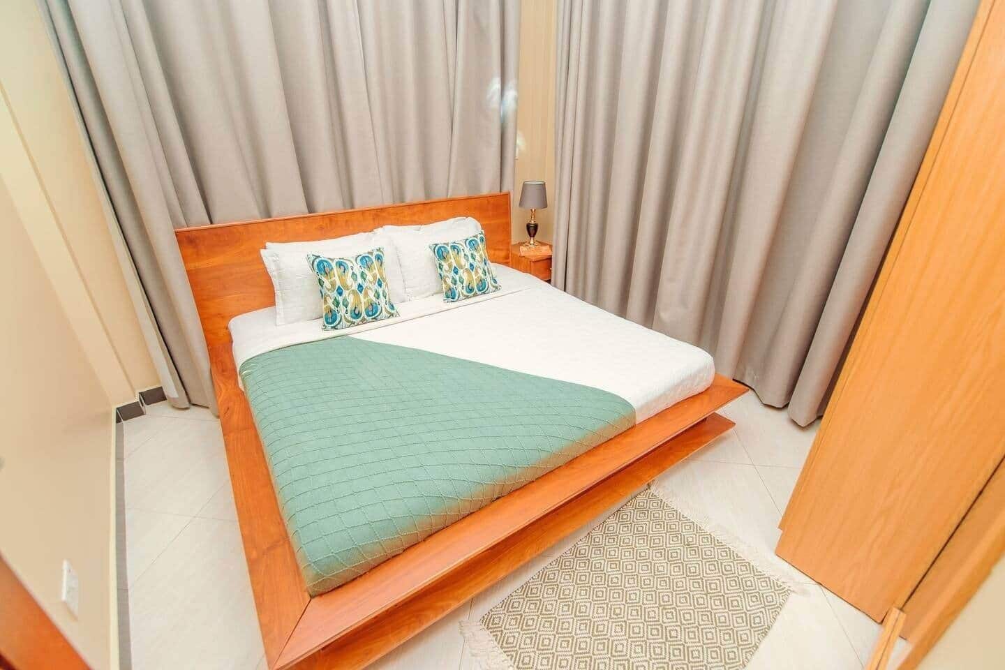 Ein Schlafzimmer mit einem Bett, Vorhängen, einem Nachttisch und einer Lampe.
