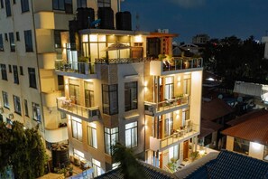 A multi-story building with balconies, large windows, and outdoor seating areas. - The Hidden Charm- Private Apt- Wi-Fi-Easy access to town (Dar es Salaam)
