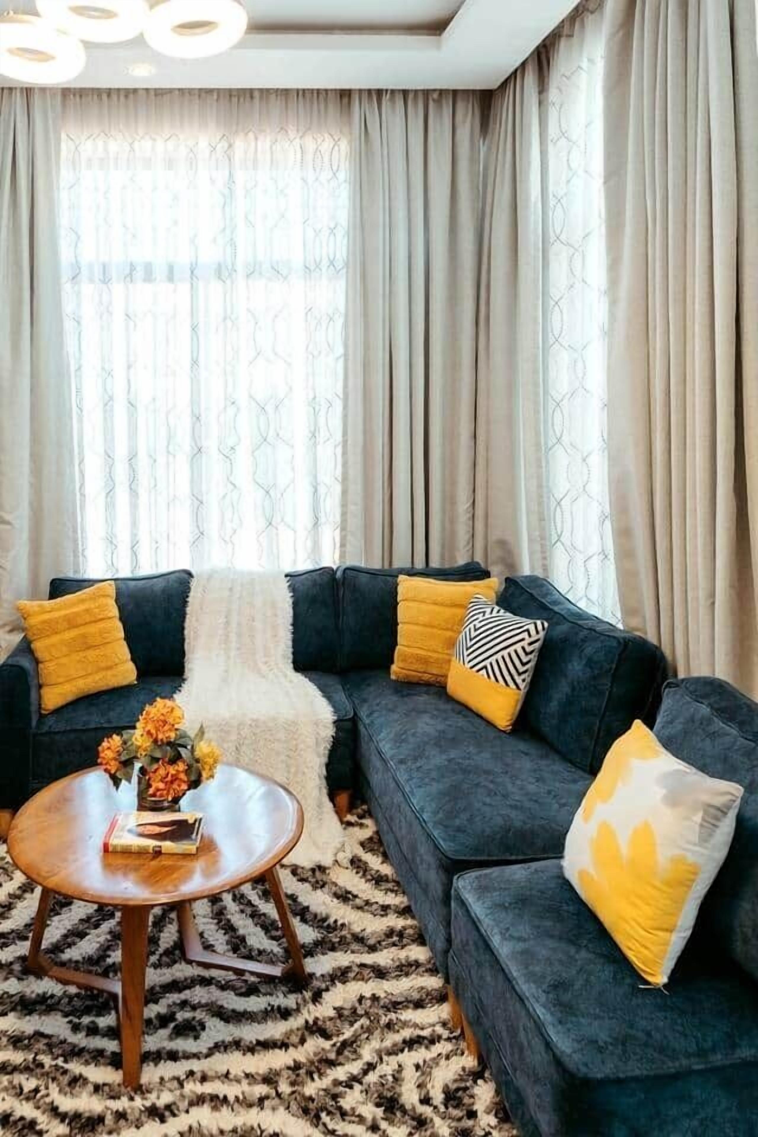 A living room with a dark-colored sofa, a round wooden coffee table, and a patterned rug.