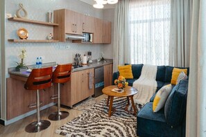 Ein kompakter Wohnraum mit Küchenzeile, einer Couch mit Zierkissen und einem Couchtisch.