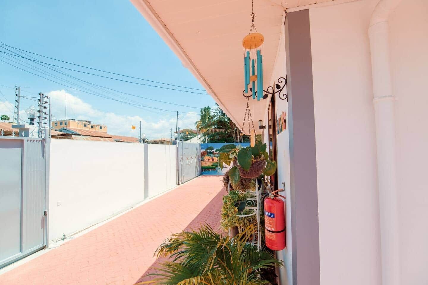 Varanda com vista para a rua, um extintor de incêndio e móbiles de vento pendurados.