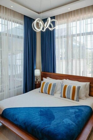 Ein Hotelzimmer mit einem großen Bett, einem Holzkopfstück und einer modernen Pendelleuchte.
