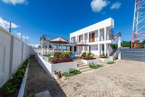 Ein modernes Gebäude mit Pool, Sitzgelegenheiten im Freien und einer Treppe zu einem Balkon.