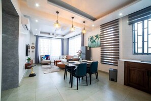 A modern living room with a dining area, large windows, and a kitchen with a built-in oven. - Seashells Private Apt - Kitchen| Pool |Wi-Fi | Beachwalk (Jambiani Kikadini)