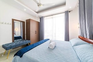 A hotel room with a bed, a bench, a wardrobe, and a window with curtains. - Ocean Breeze retreat - 7 min Beach walk | Pool (Jambiani Kikadini)
