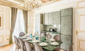 A dining area with a glass table set for six, surrounded by chairs. - LUXURIOUS HERITAGE PARISIAN APARTMENT WITH GOLD-LEAF INTERIORS & JACUZZI (Paris)