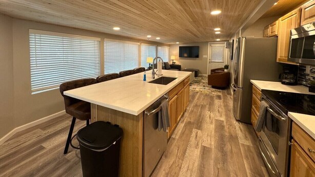 Una cocina moderna con una isla central, armarios de madera y electrodomésticos integrados.