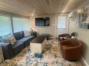 Ein Wohnzimmer mit einer Couch, einem Hocker, einem Couchtisch und einem braunen Ledersessel.
