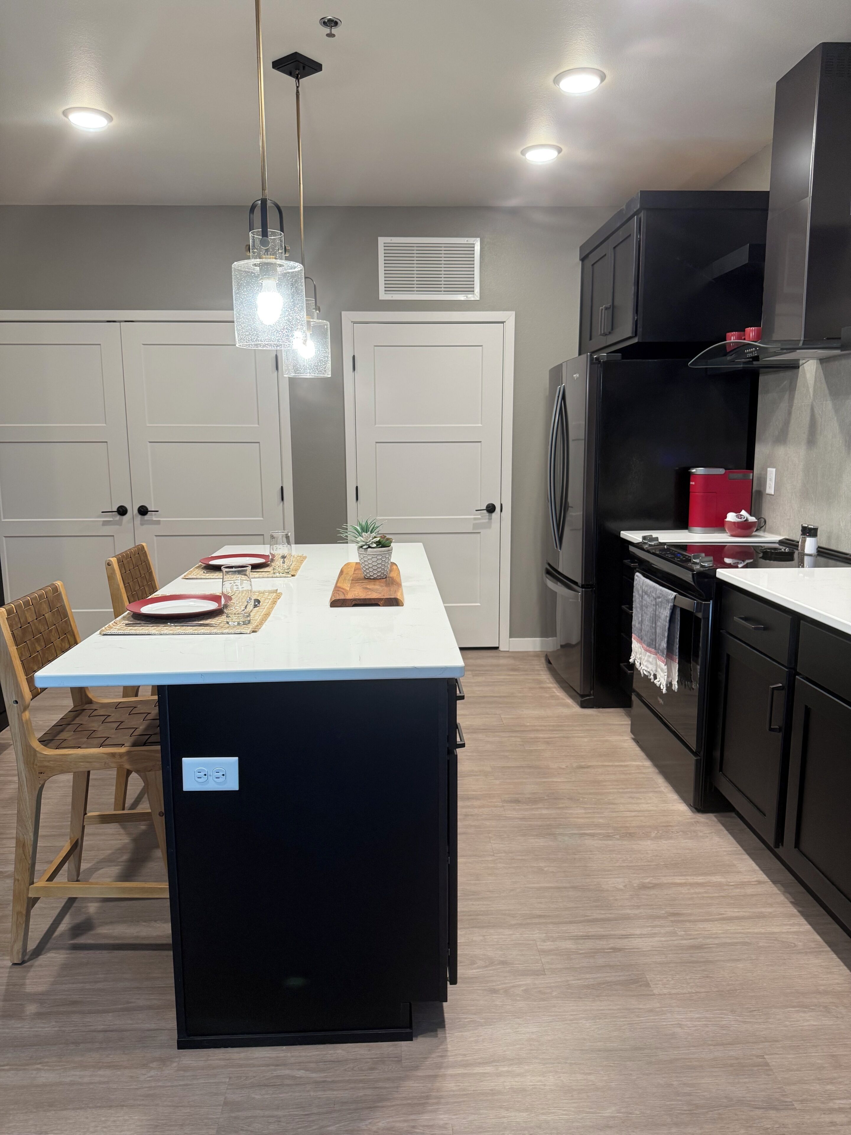 A modern kitchen with a central island, black cabinetry, and a white countertop.