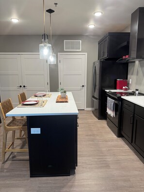 A modern kitchen with a central island, black cabinetry, and a white countertop.
