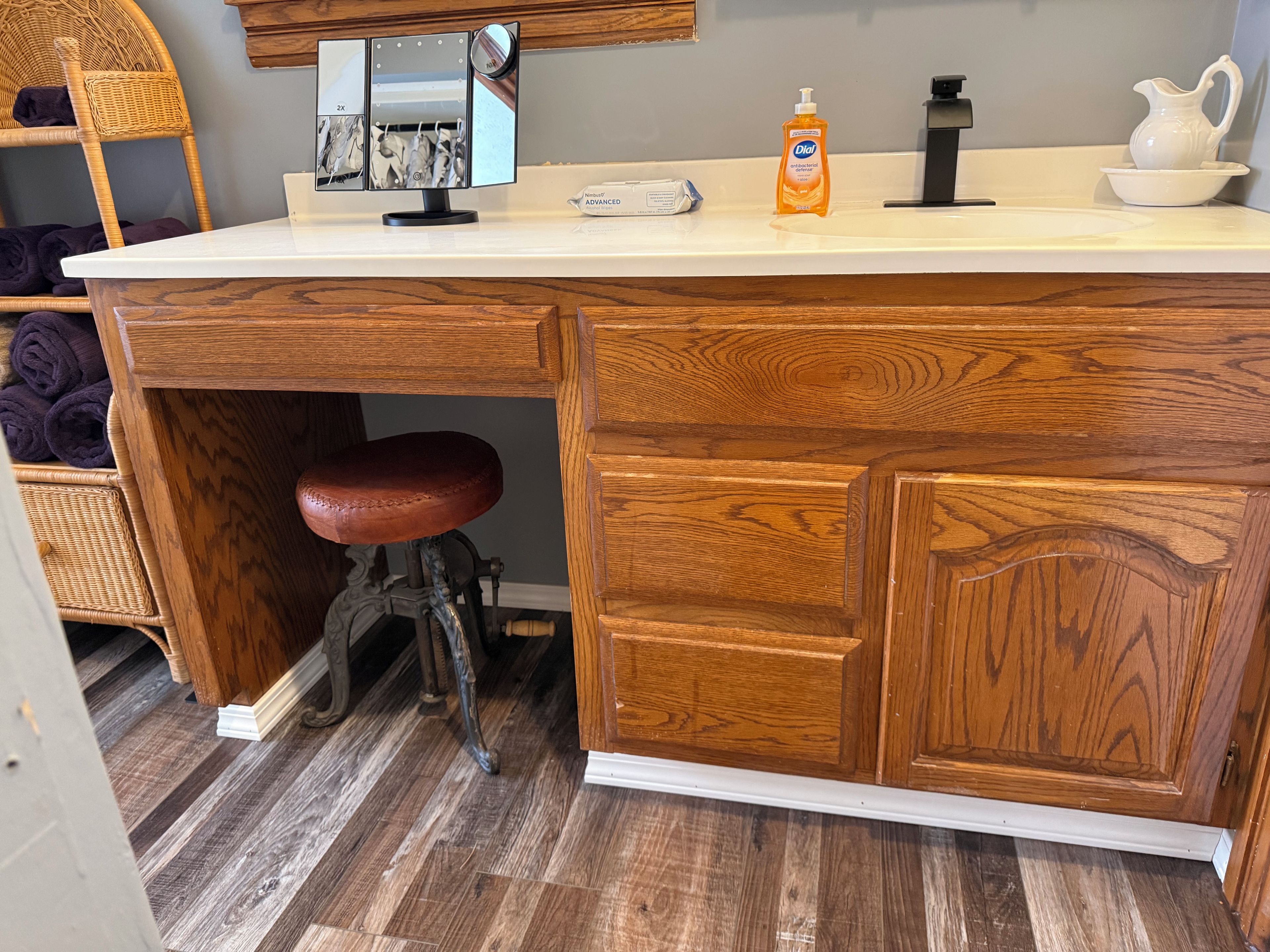 A kitchen with a wooden countertop, a sink, a bottle of hand soap, and a wicker chair.