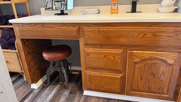 A kitchen with a wooden countertop, a sink, a bottle of hand soap, and a wicker chair.