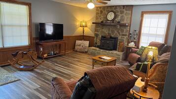 Una sala de estar con televisión, chimenea, mecedora y sofá.