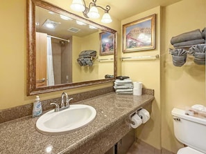 Un bagno con lavandino, specchio, porta asciugamani e water.
