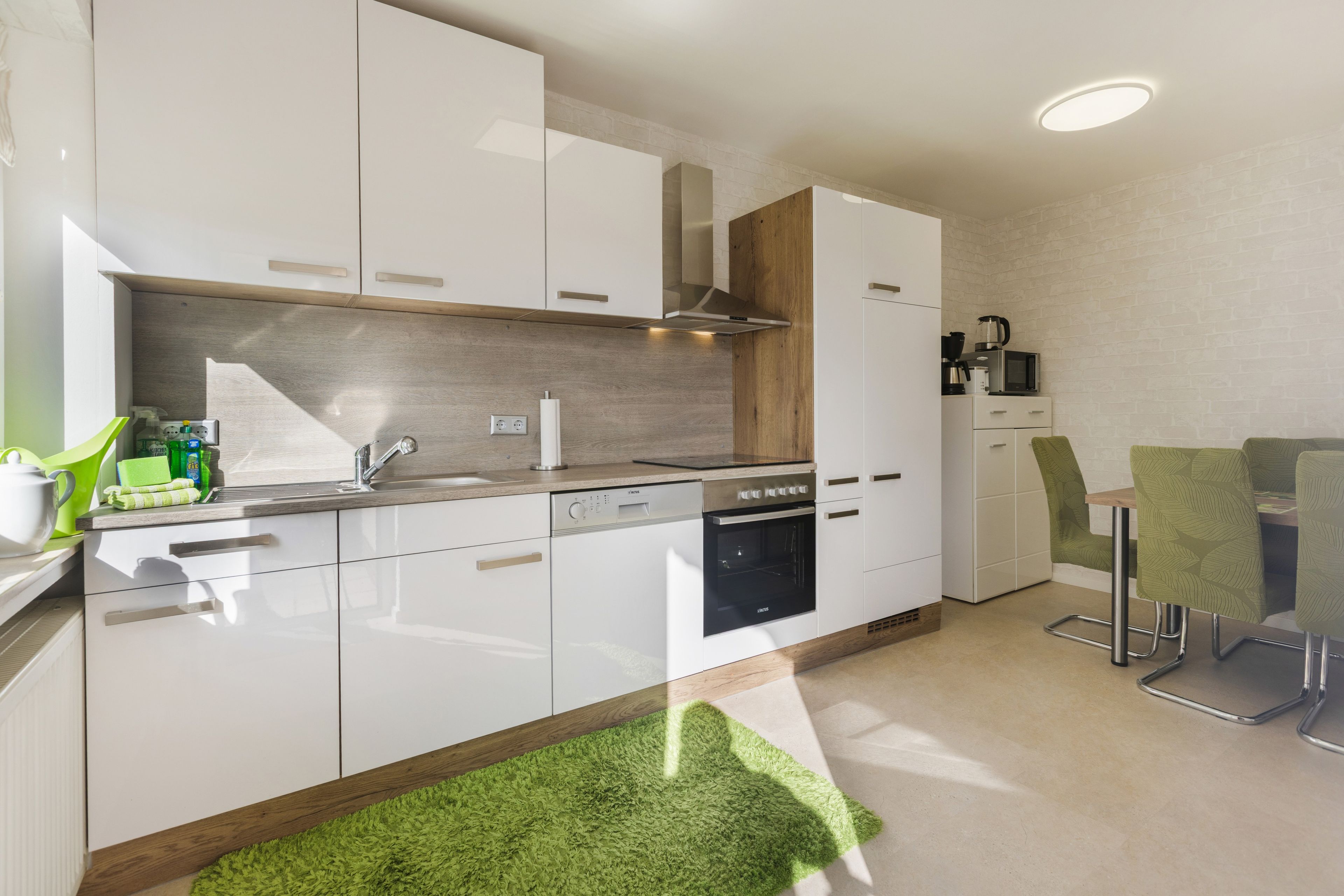 A modern kitchen with white cabinetry, a built-in oven, and a microwave.