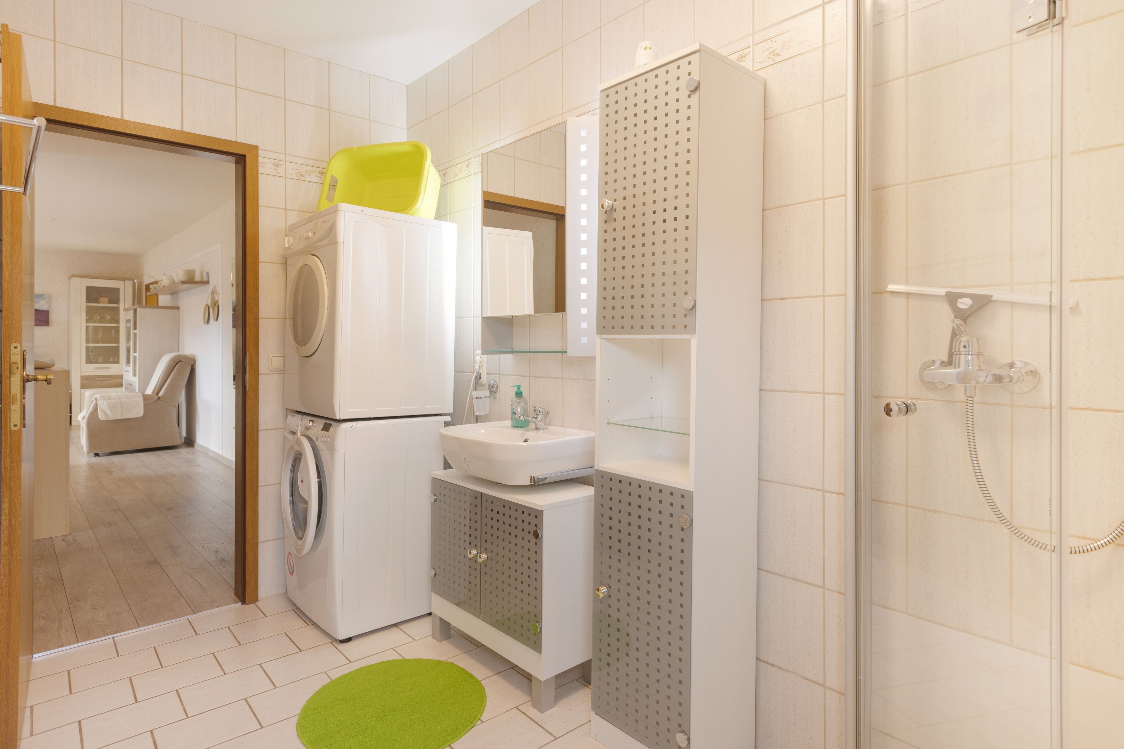 Ein kleines Hotelbad mit Waschmaschine, Waschbecken und Dusche.