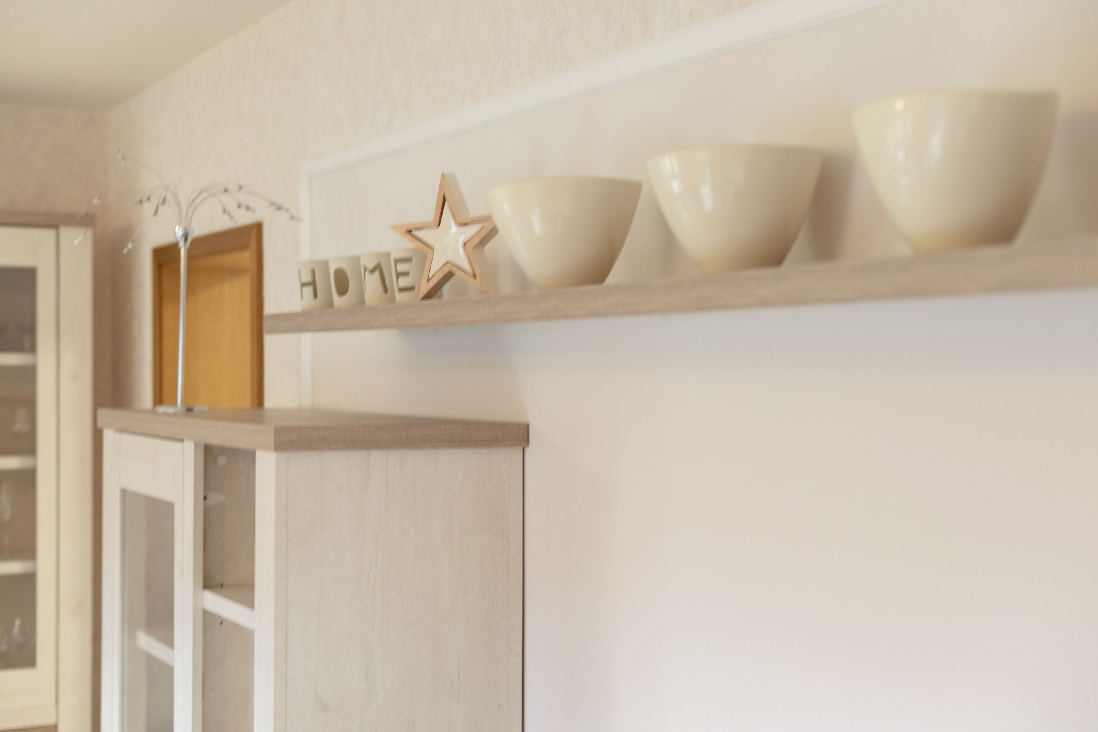 Una repisa de cocina con objetos decorativos, incluyendo una estrella de madera y bloques de letras que deletrean 'HOME'.