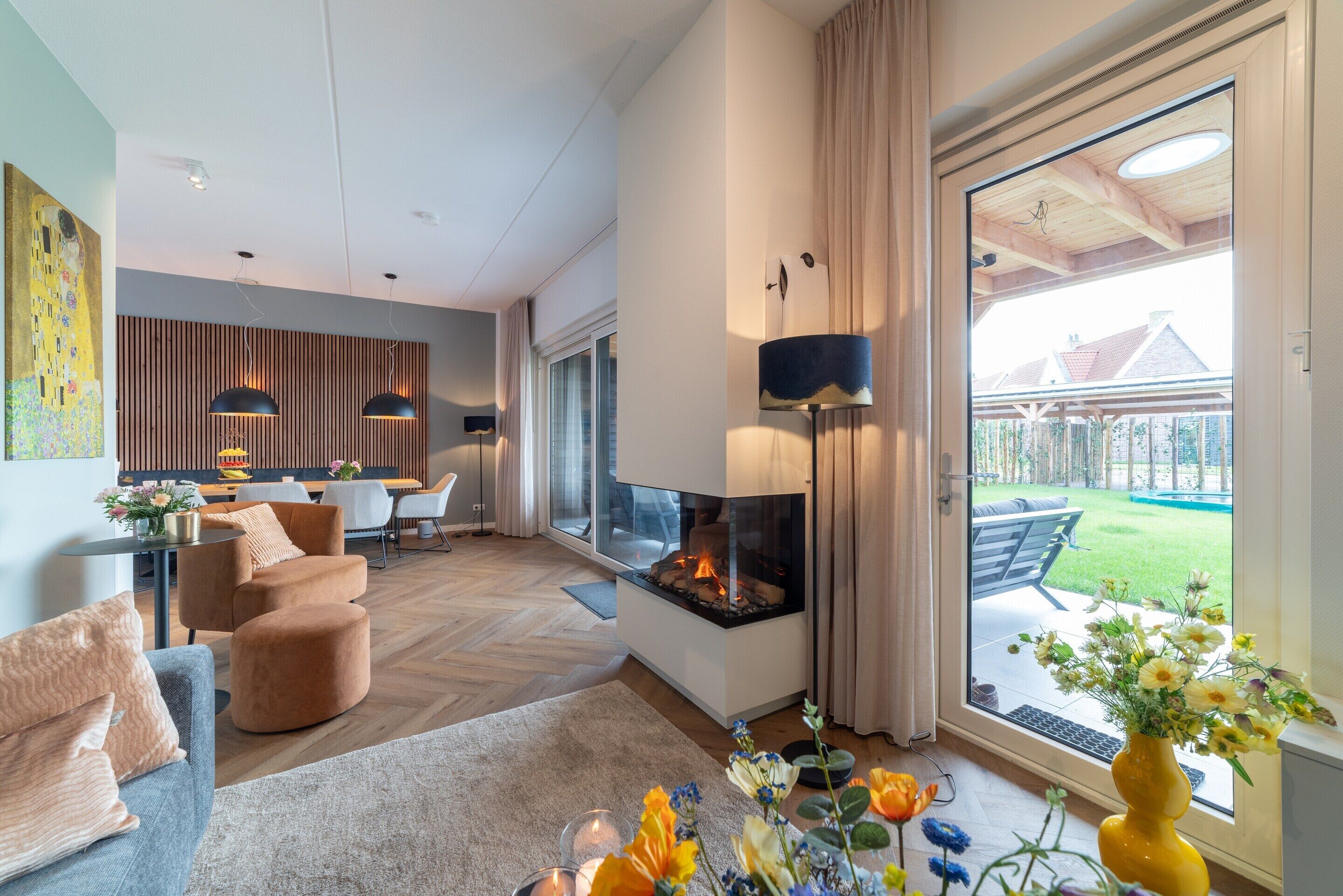 Ein modernes Wohnzimmer mit Kamin, bequemer Sitzgelegenheit und Blick ins Freie.