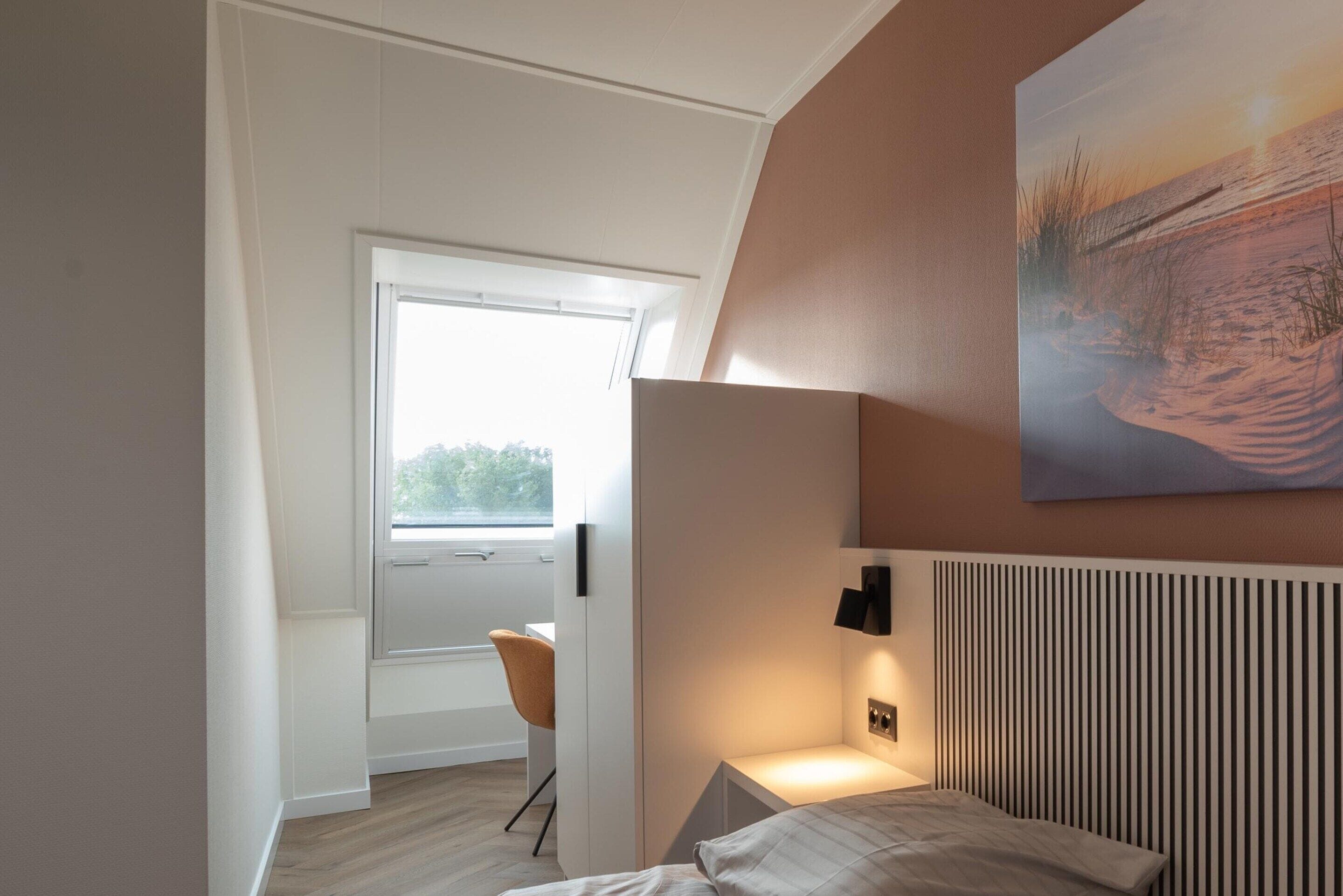 A modern bedroom with a bed, bedside table, and a painting on the wall.