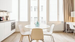 A modern kitchen with white cabinets, a stove, and a dining area with a round table and white chairs. - Pirandello 3 - Studio Apartment, Sleeps 4 (Milano)