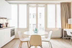 Una cucina moderna con mobili bianchi, un fornello e un'area pranzo con un tavolo rotondo e sedie bianche.