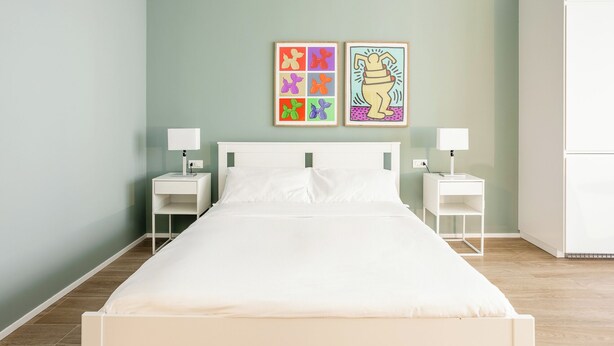 A bedroom with a bed, two bedside tables, a wardrobe, and two wall-mounted artworks. - Pirandello 3 - Studio Apartment, Sleeps 4 (Milano)