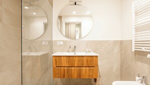 A modern bathroom with a glass shower enclosure, a wooden vanity with a mirror, and a white sink. - Pirandello 3 - Studio Apartment, Sleeps 4 (Milano)