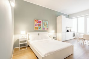A modern hotel room with a bed, bedside tables, a desk, and a kitchenette. - Pirandello 3 - Studio Apartment, Sleeps 4 (Milano)