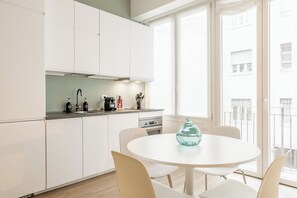 A modern kitchen with white cabinets, a round dining table, and a view of the outside. - Pirandello 3 - Studio Apartment, Sleeps 4 (Milano)