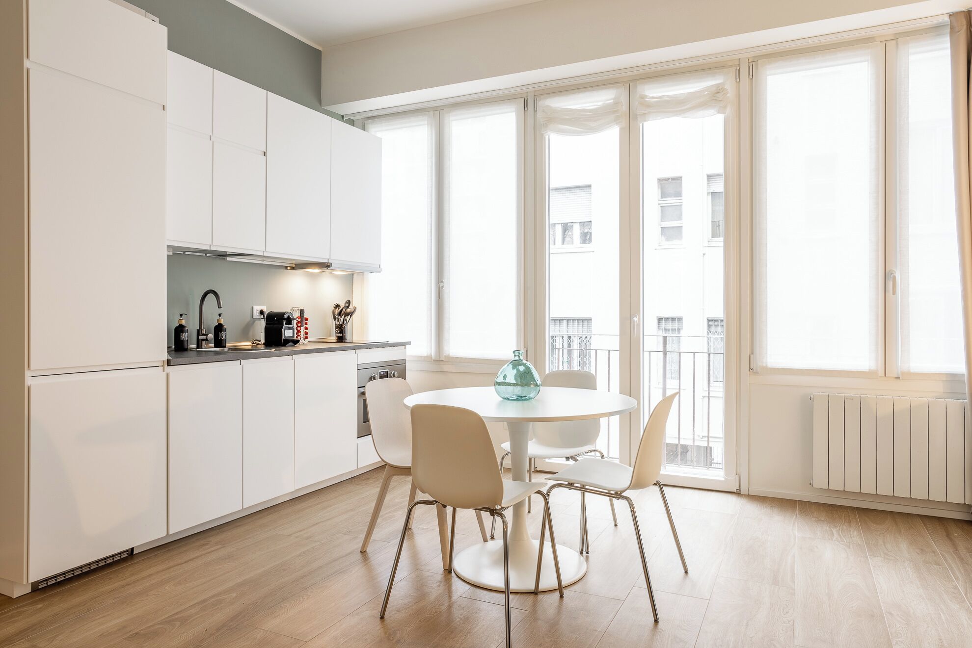 A modern kitchen with white cabinets, a round dining table, and chairs.