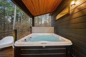 A hot tub on a wooden deck with a view of a forest. - IIII Pines + a Cone: Sleeps 18, Hot Tub, Game Room (Hochatown)