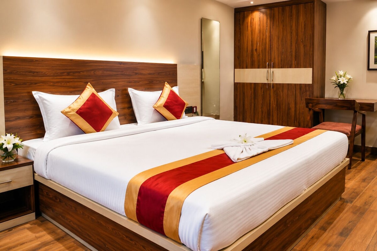 A hotel room with a large bed, wooden headboard, a desk, and a chair.
