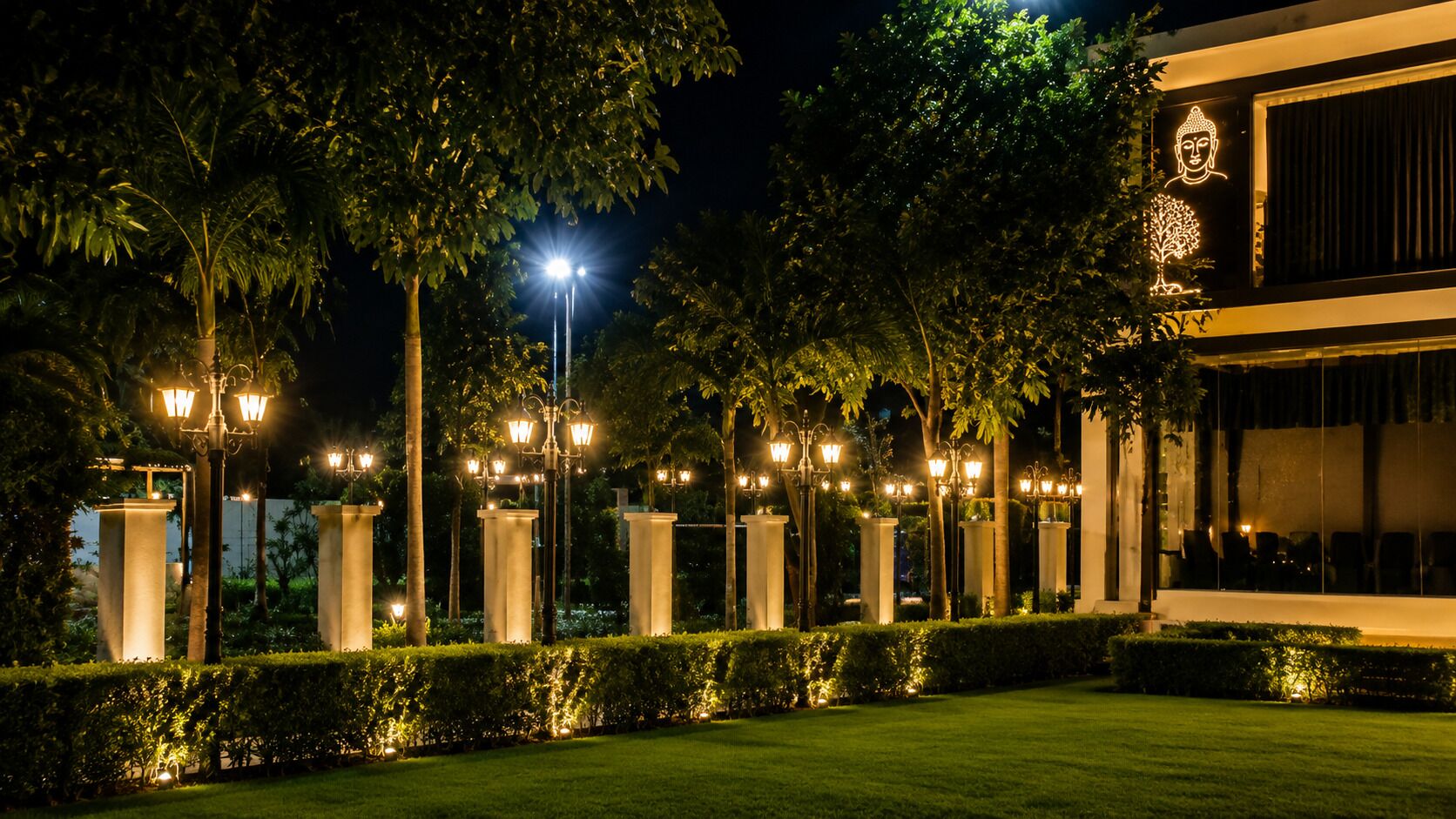 A well-lit outdoor area with a series of columns and a building with a Buddha statue.