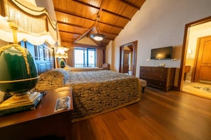 Quarto com cama grande, teto de madeira, televisão e escrivaninha com globo.