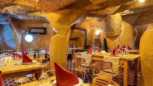 An underground restaurant with tables set for dining, featuring a cave-like interior with natural rock formations. - Erta Soyak Hotel Sarıkamış (Sarıkamış)