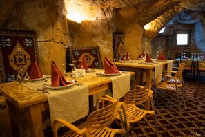 A dining area with tables set for multiple guests, wooden chairs, and traditional decor.