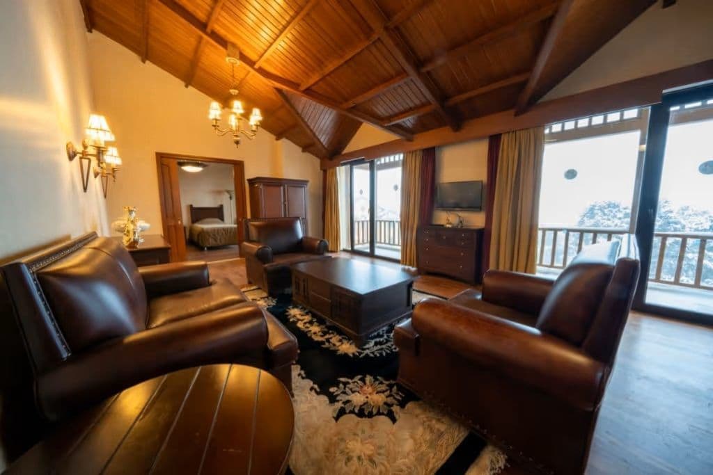 A spacious living room with leather sofas, a coffee table, and a chandelier.