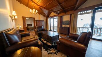 A spacious living room with leather sofas, a coffee table, and a chandelier.