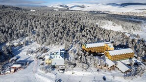 A snow-covered landscape with a lodge featuring multiple buildings, including a prominent yellow structure. - Erta Soyak Hotel Sarıkamış (Sarıkamış)