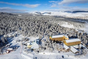 Schneebedeckte Landschaft mit einer Lodge, bestehend aus mehreren Gebäuden, darunter ein markantes, gelbes Bauwerk.