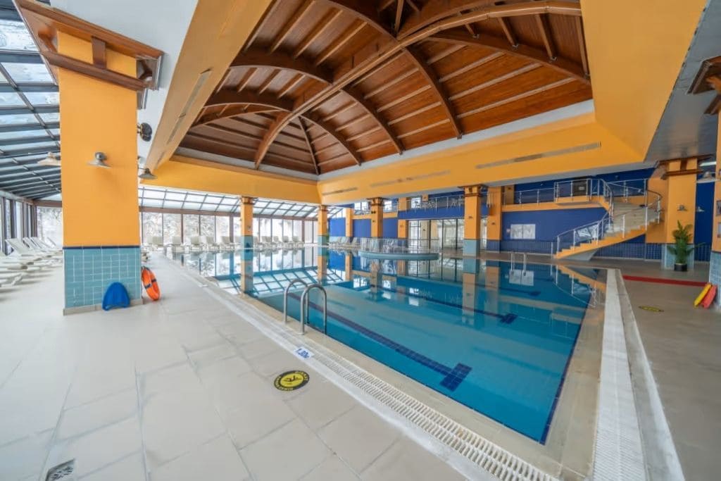 An indoor swimming pool with a high ceiling and a glass enclosure.