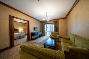 A hotel room with a living area featuring a sofa, a coffee table, and a television.