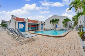 A pool area with lounge chairs, a pool, and a building with a 'No Diving' sign. - 2-bedroom Cozy Beach Getaway w/ Screened Lanai (Madeira Beach)