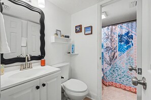 A bathroom with a white sink, a toilet, and a shower curtain with a floral pattern. - 2-bedroom Cozy Beach Getaway w/ Screened Lanai (Madeira Beach)