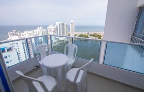 A balcony with a table and chairs, overlooking a cityscape and the sea. - Vrbo Property (Cartagena de Indias)
