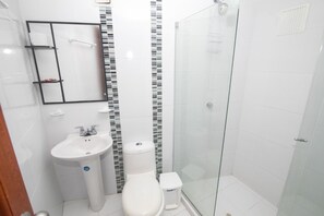 A bathroom with a white sink, toilet, and glass shower enclosure. - Vrbo Property (Cartagena de Indias)